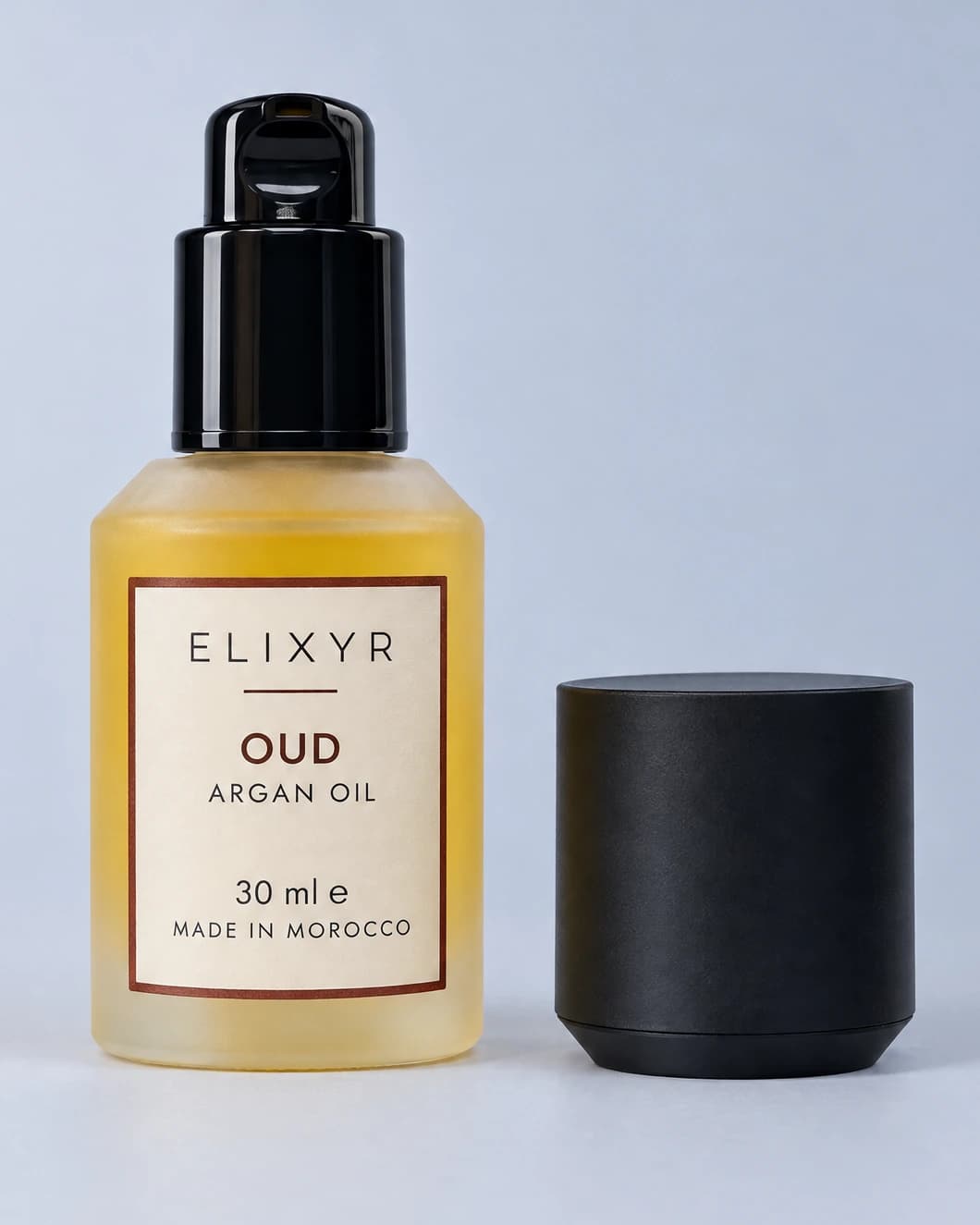 ELIXYR Oud 30ml fragranced argan oil in frosted glass, glossy black pump exposed with the matte black cap beside it